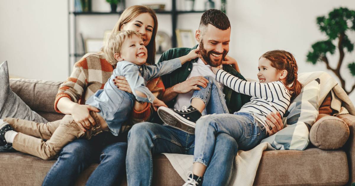 Een vader, moeder en 2 kinderen hebben samen plezier en spelen op de bank